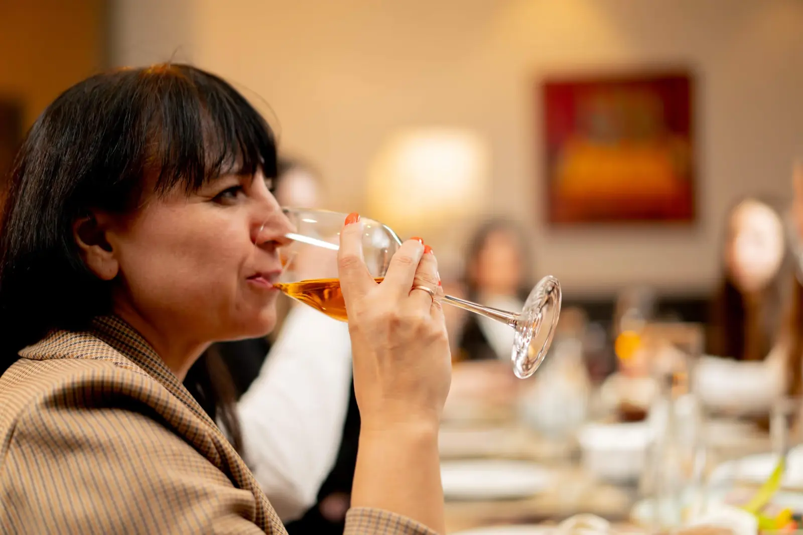 Woman drinking a glass of wine at a busy dinner party.