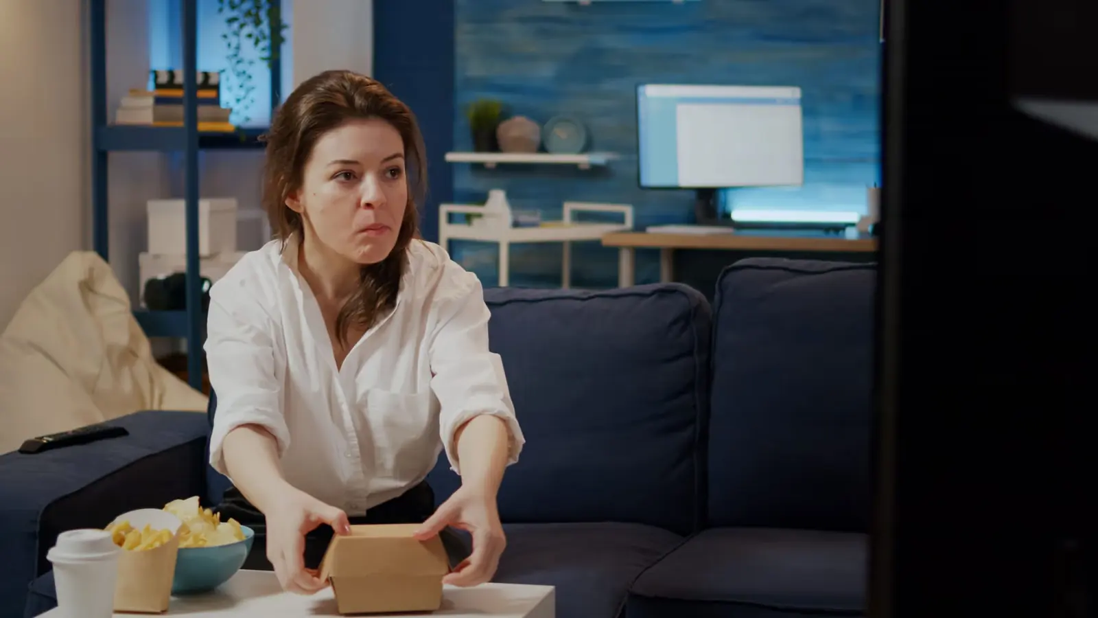 Stressed woman opening a takeaway box at her coffee table at home.