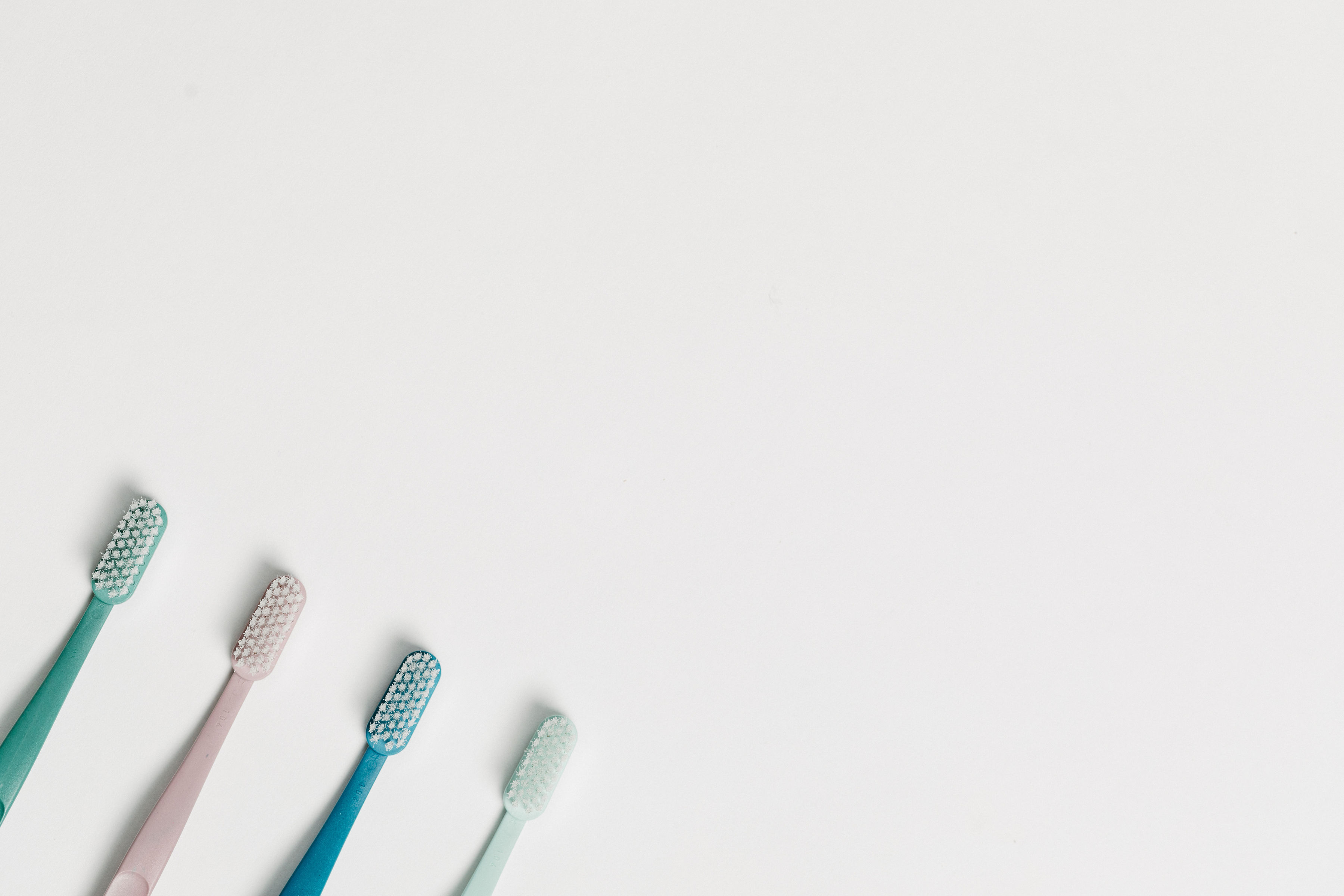 Four pastel-colored toothbrushes arranged diagonally on a white background.