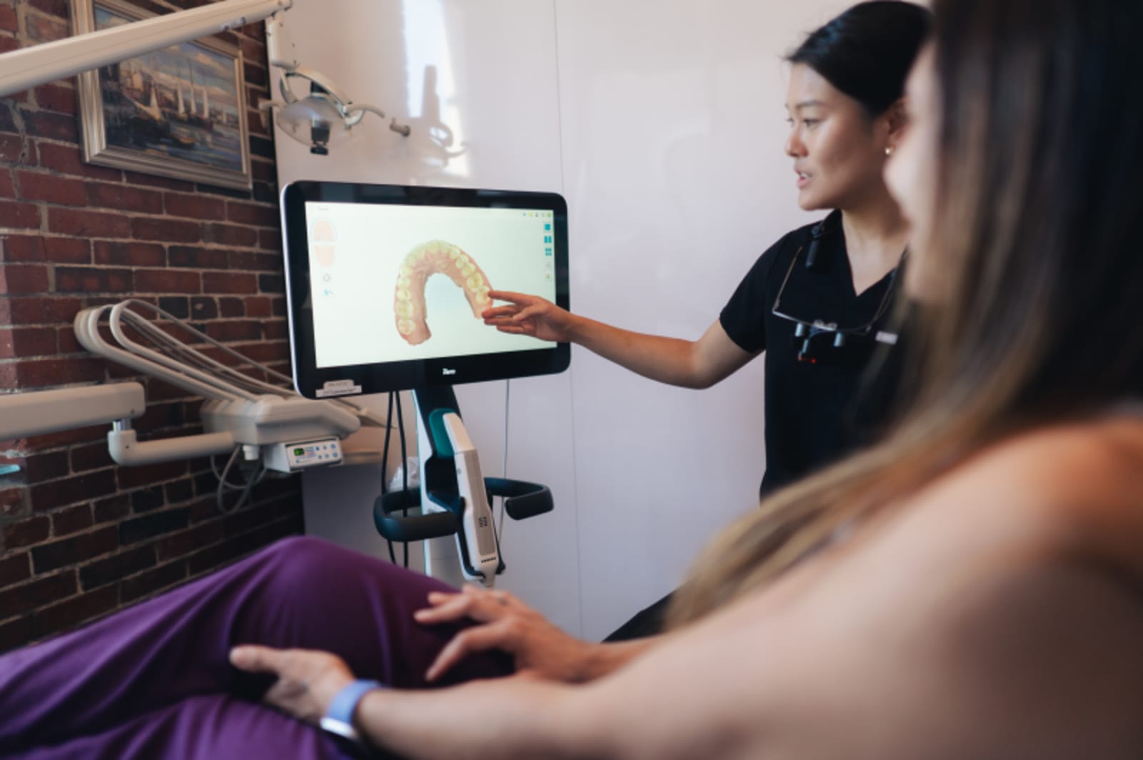 Dentist explaining treatment plan to patient using digital display