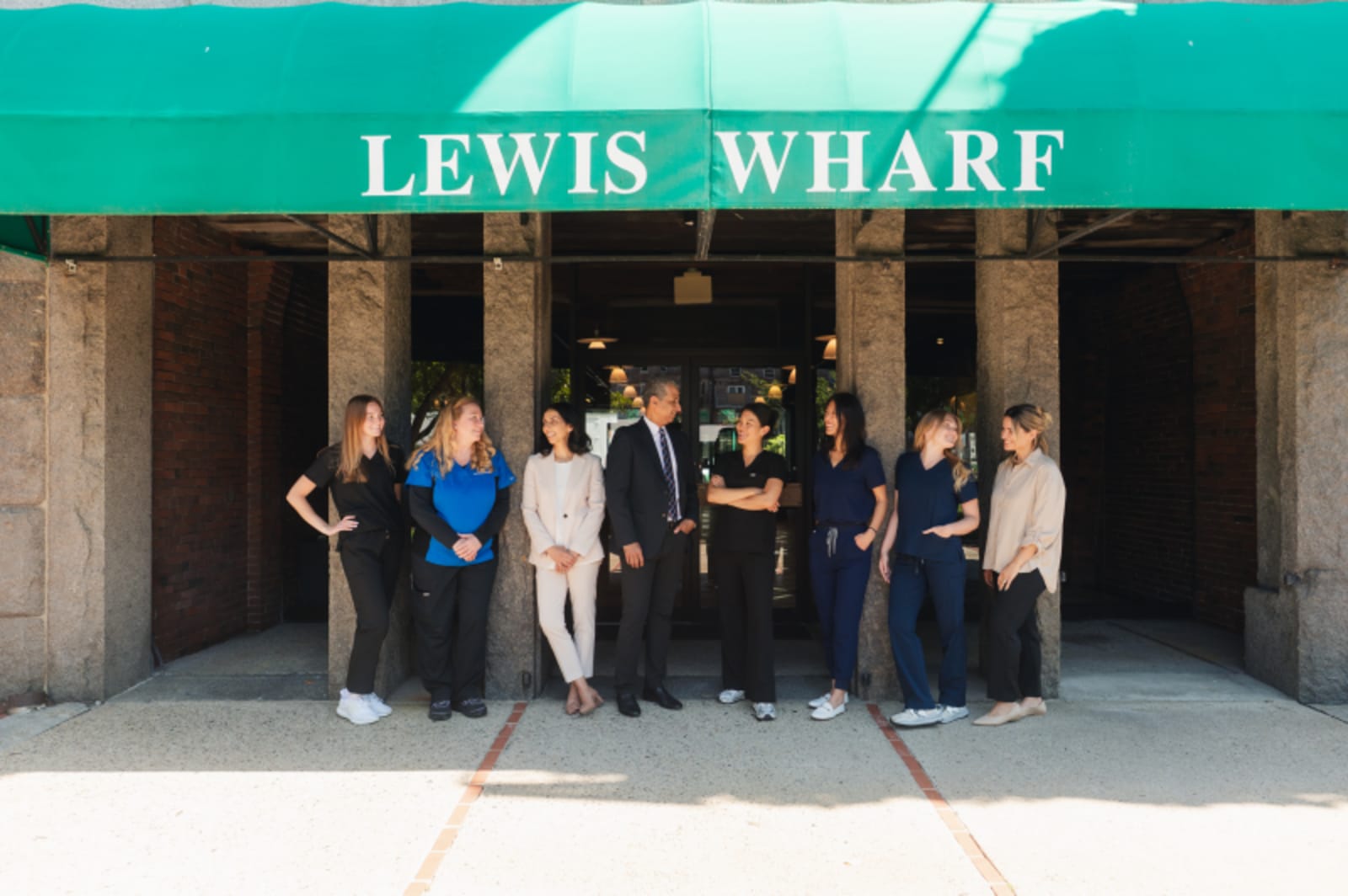 Lewis Wharf Dental team posing together outside their Boston office entrance.