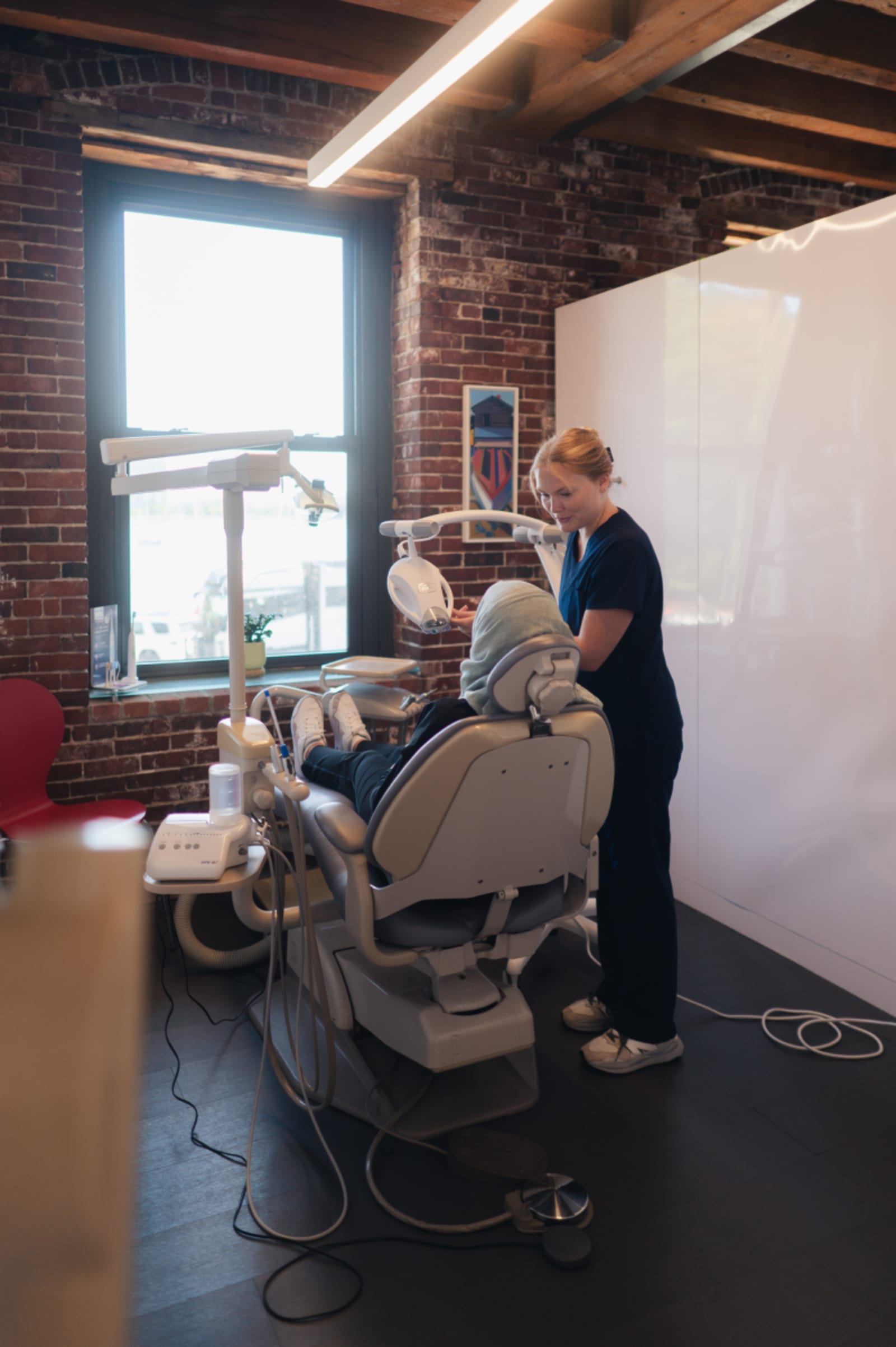 Dentist working with patient in clinical treatment chair with window view