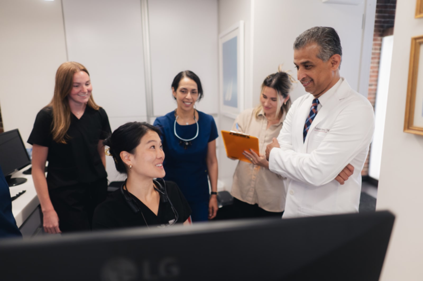 Dental team discussing treatment plan with patient at computer workstation