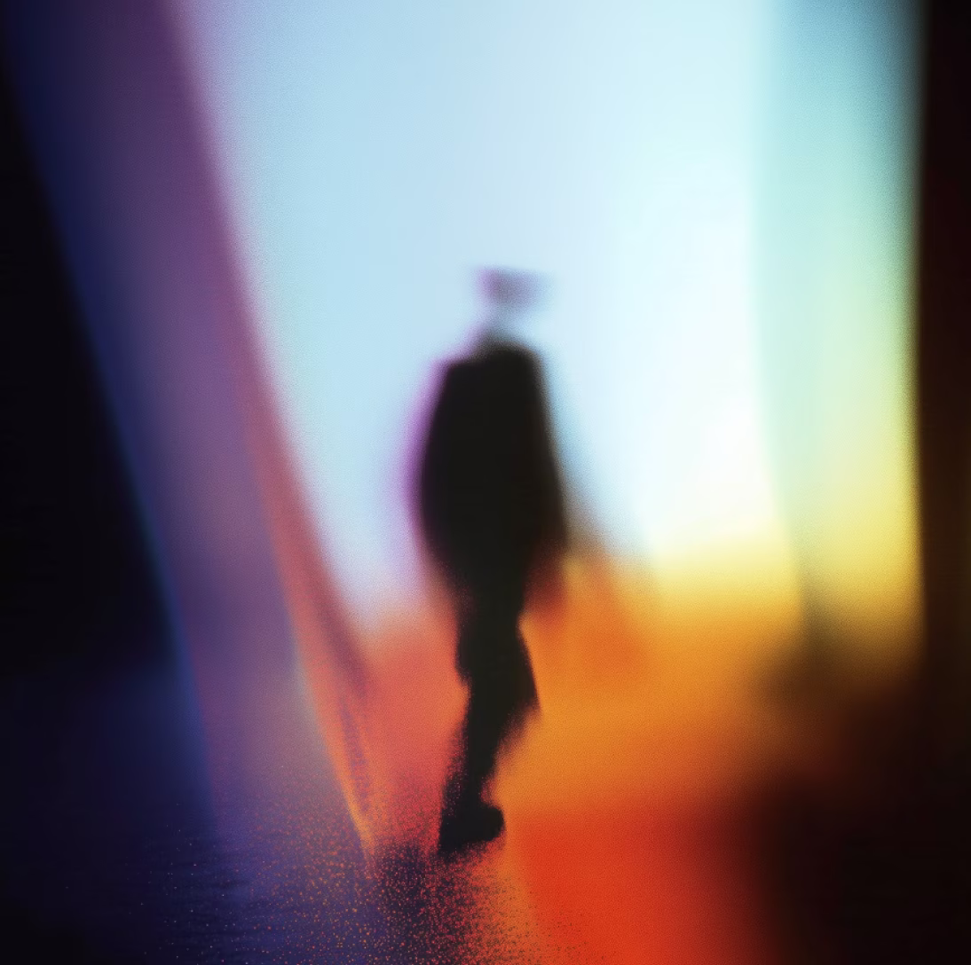 Blurry silhouette of a person walking against a background of multicolored light gradients.