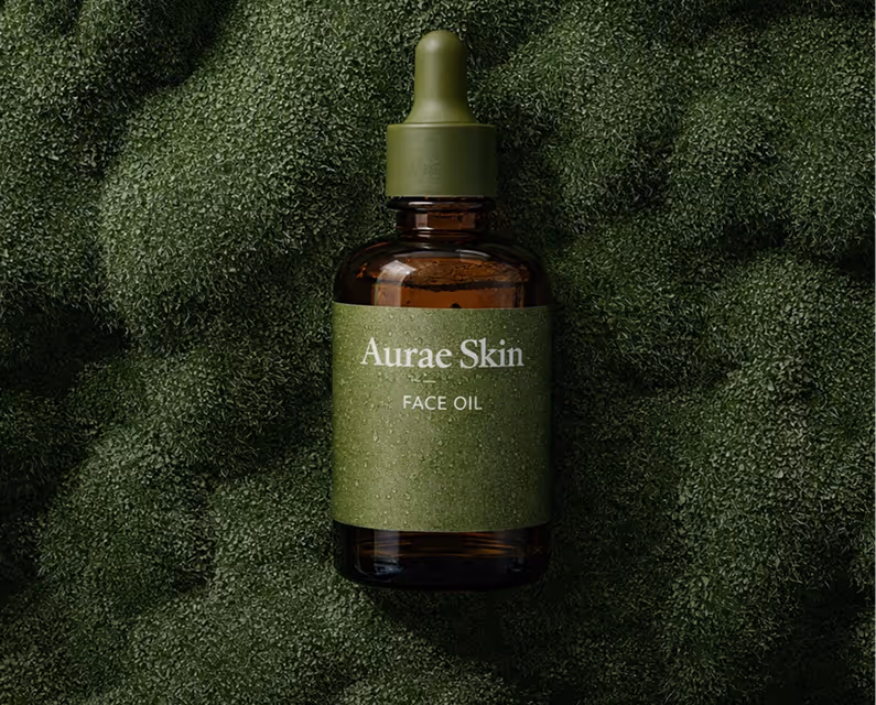 Dark amber dropper bottle labeled Aurae Skin Face Oil on a textured green moss background.