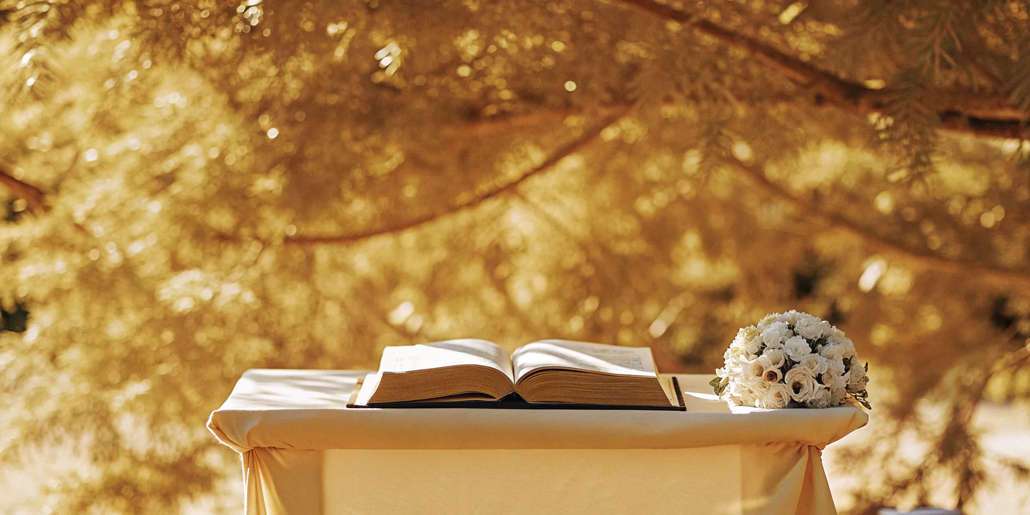 Open Bible and wedding bouquet on an outdoor altar for wedding sermon ideas.