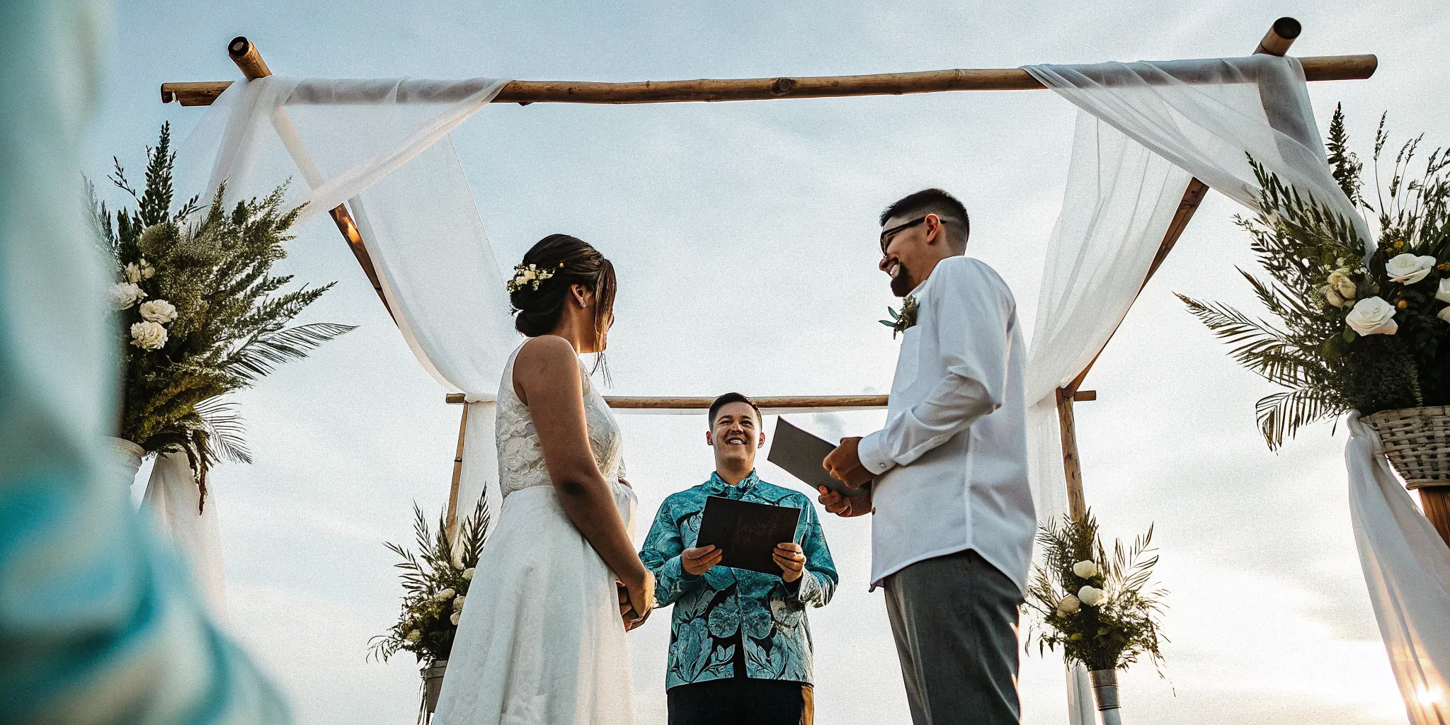 Wedding officiant, couple, and floral arch at a secular ceremony.