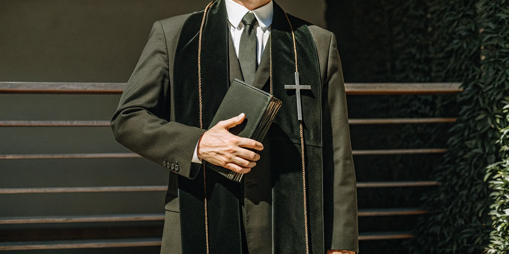 A man holding a Bible and cross after learning how to be an ordained minister.