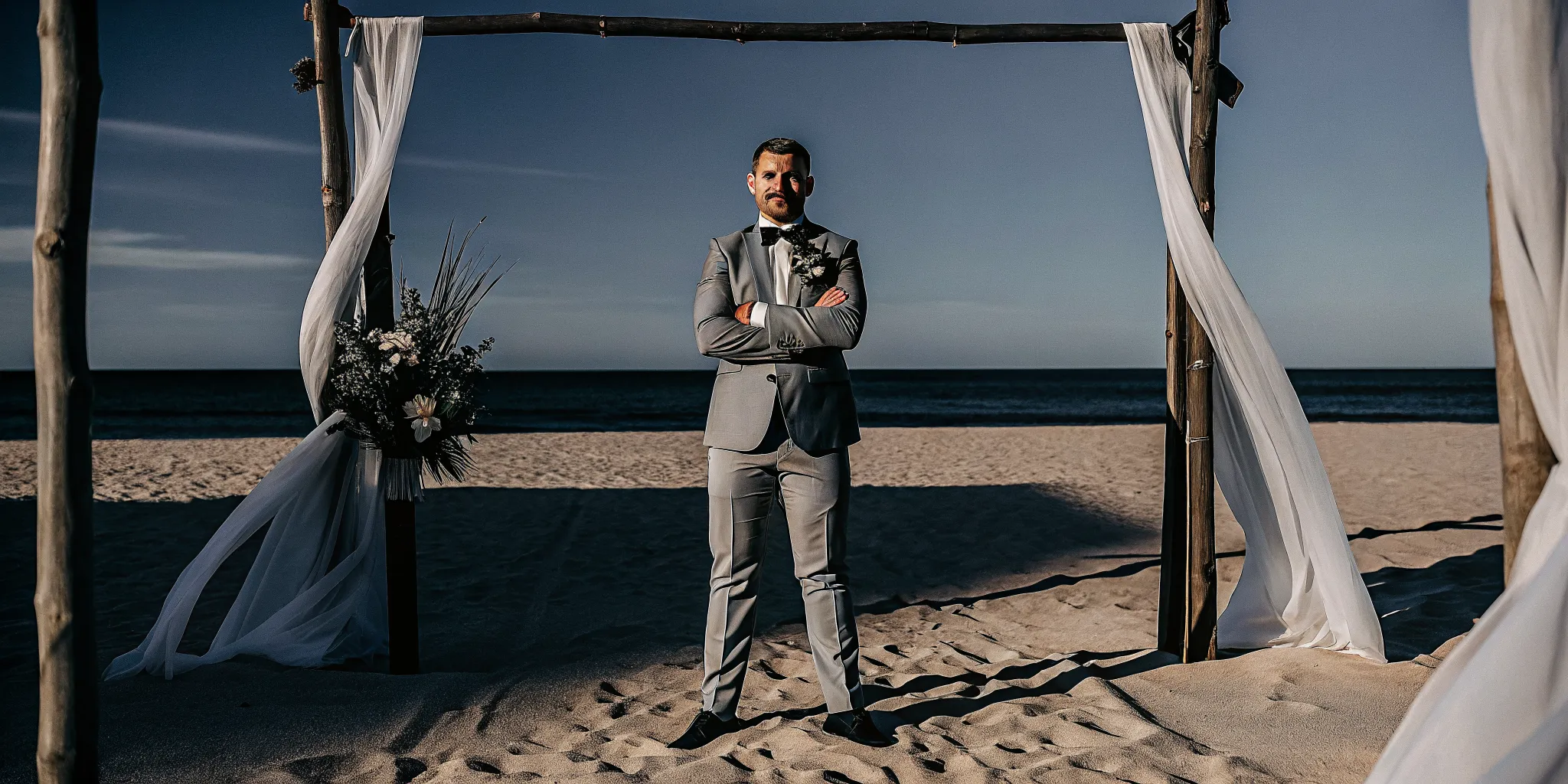 Groom at a beach wedding arch, waiting for the officiant to begin the ceremony script.