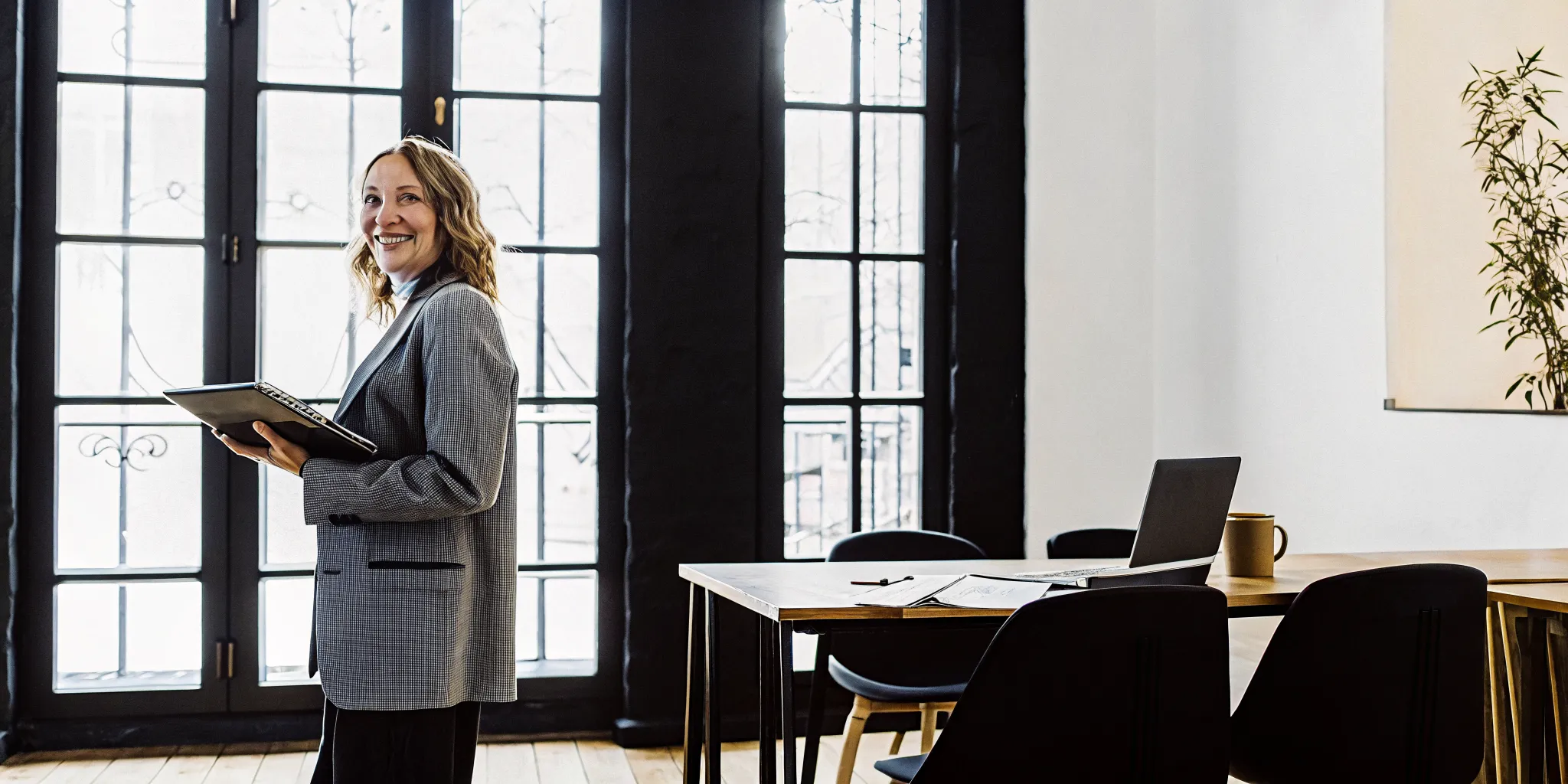 A non-denominational minister in a modern office, holding a notebook and smiling.