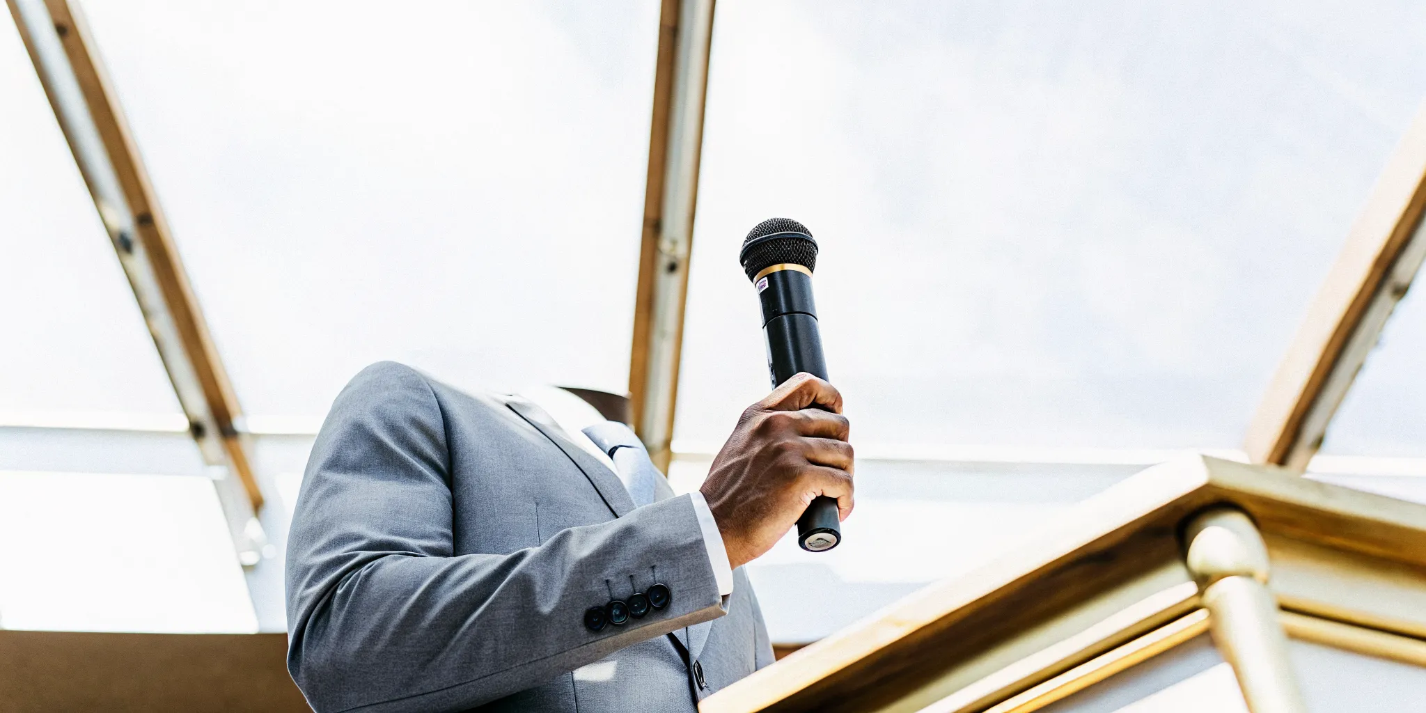 Wedding officiant showing how to use a handheld microphone with proper technique at a podium.