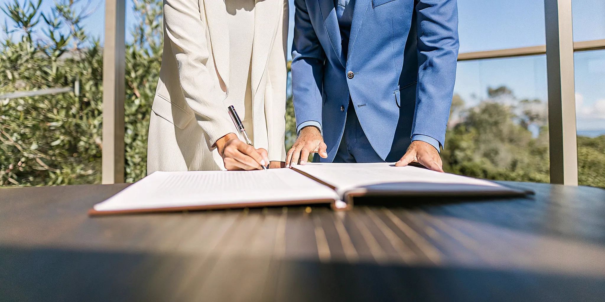 A friend officiating a wedding signs the legal marriage license with the couple.
