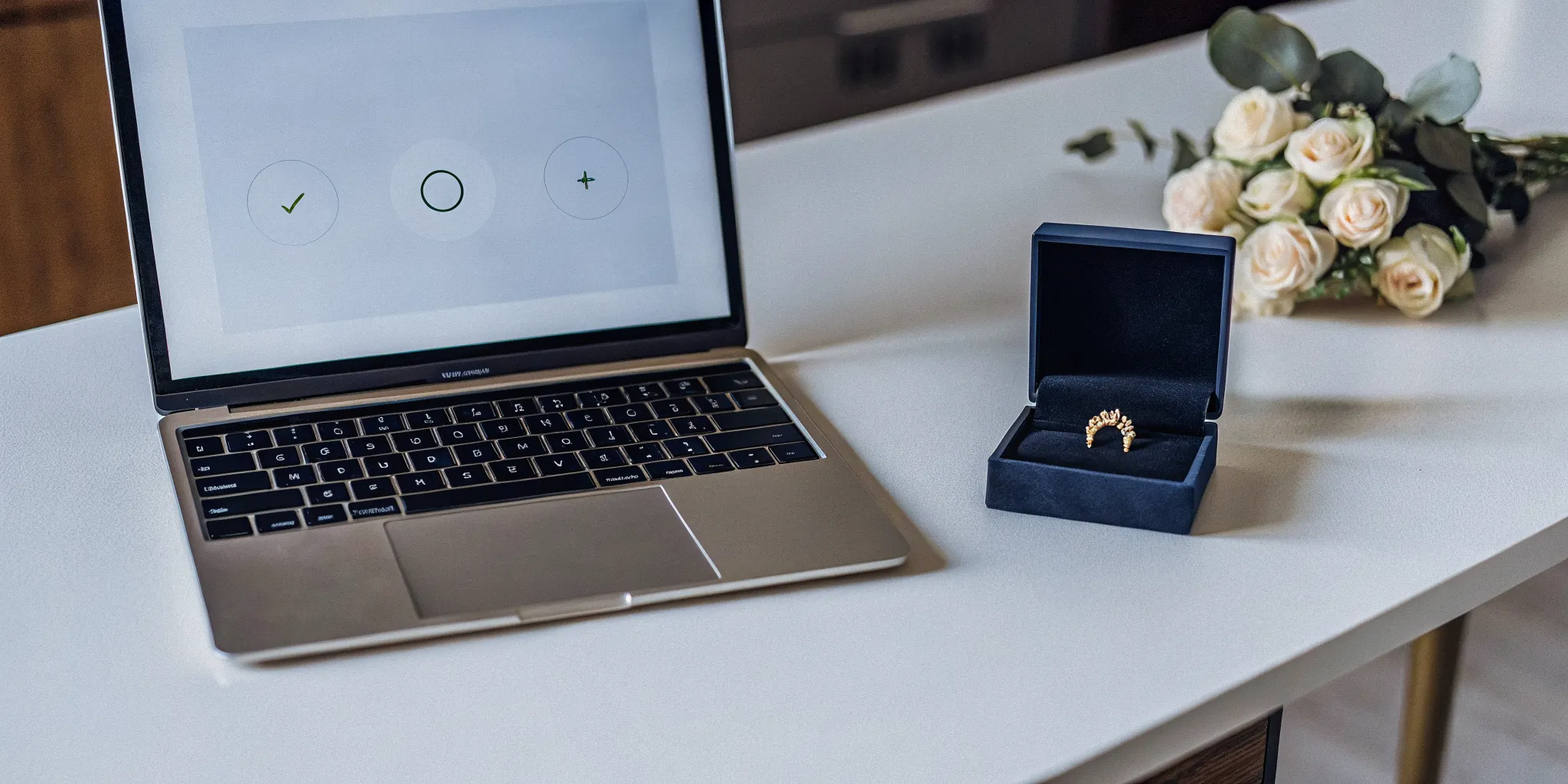 A laptop, ring box, and bouquet for an online ordination for a family wedding.