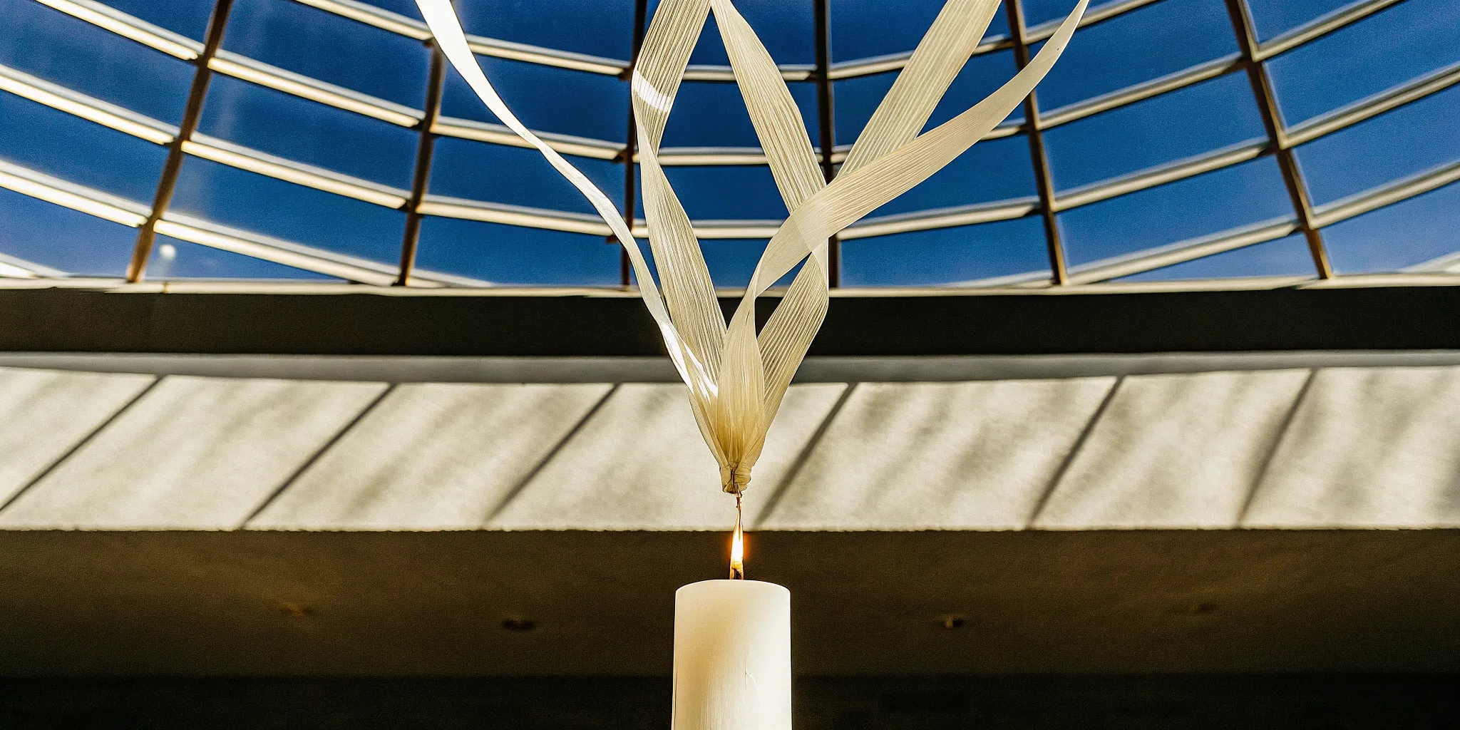 A white candle and palm leaves representing the biblical one spirit meaning.