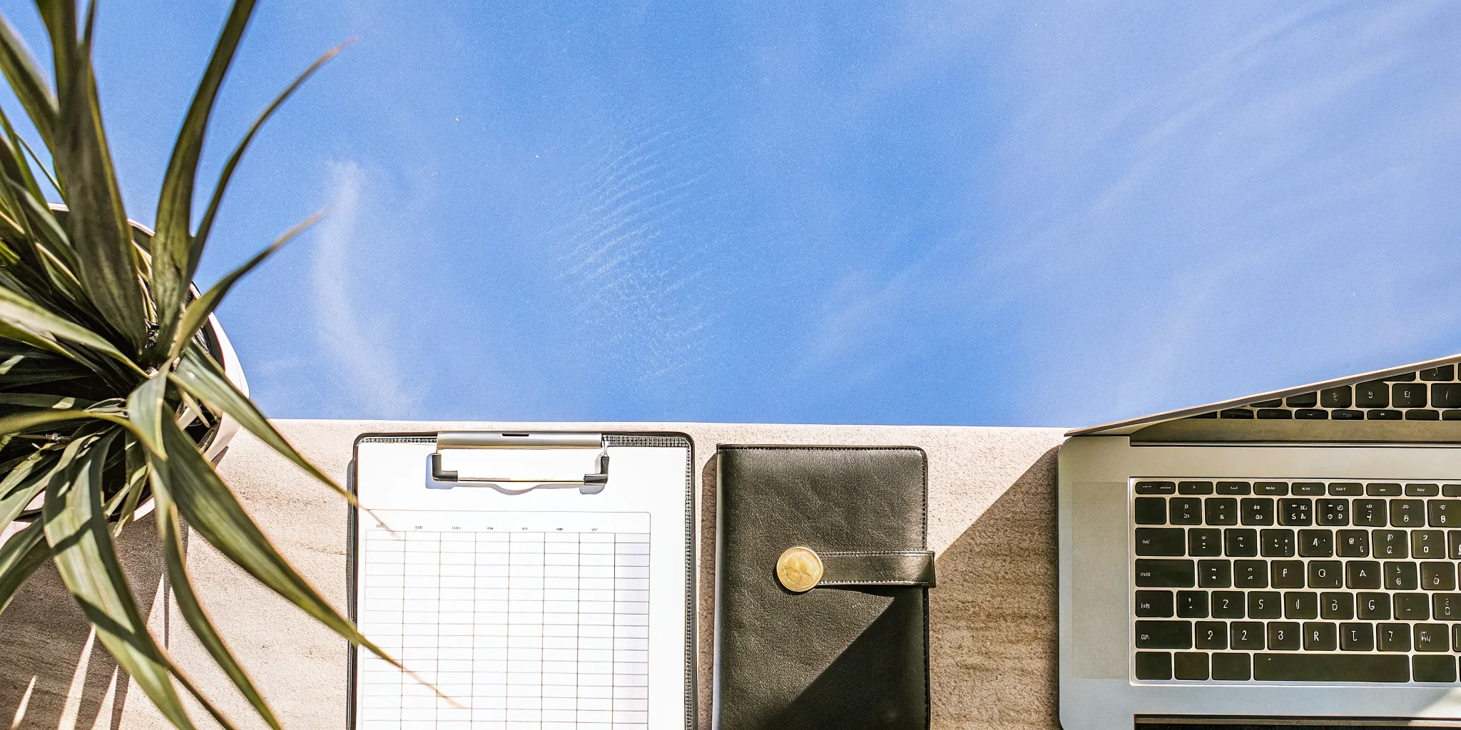 A laptop, clipboard, and planner on a desk for becoming a certified wedding officiant.