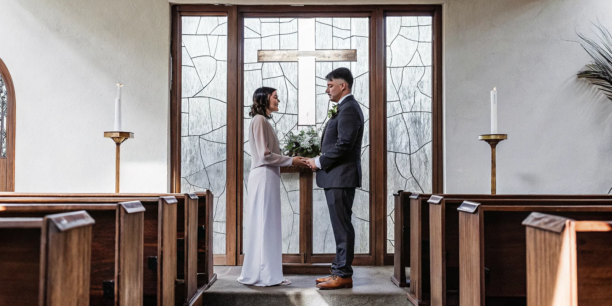 Catholic and Baptist wedding ceremony with a couple holding hands in front of a cross.