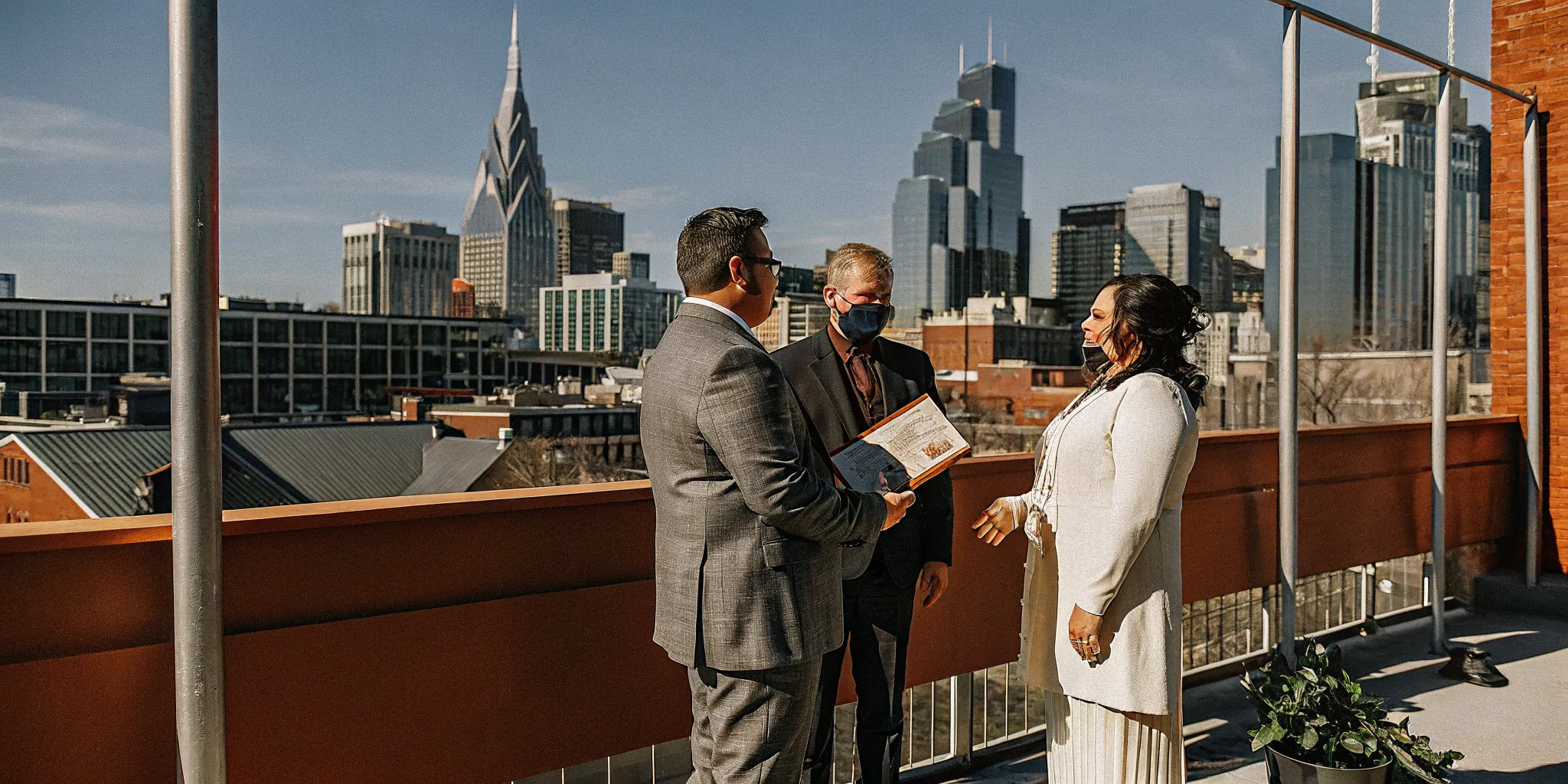 Wedding officiant with marriage license in front of Nashville skyline, serving couples after ordination.