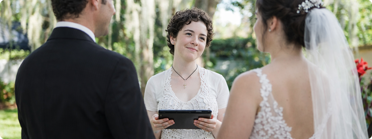 Wedding officiant conducting a ceremony for a couple outdoors.