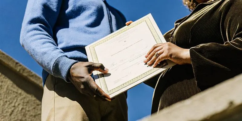 Person holding an ordination certificate outdoors near a ceremony setting