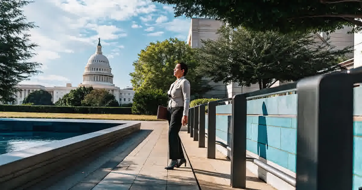 Person standing in a sunlit park near the U.S. Capitol building in Washington D.C.