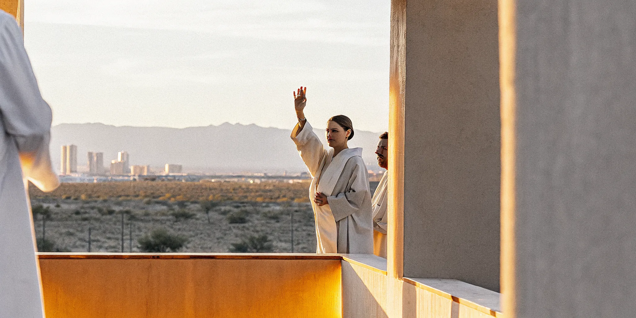 Person being ordained with raised hand, Las Vegas desert landscape with distant city skyline at golden hour