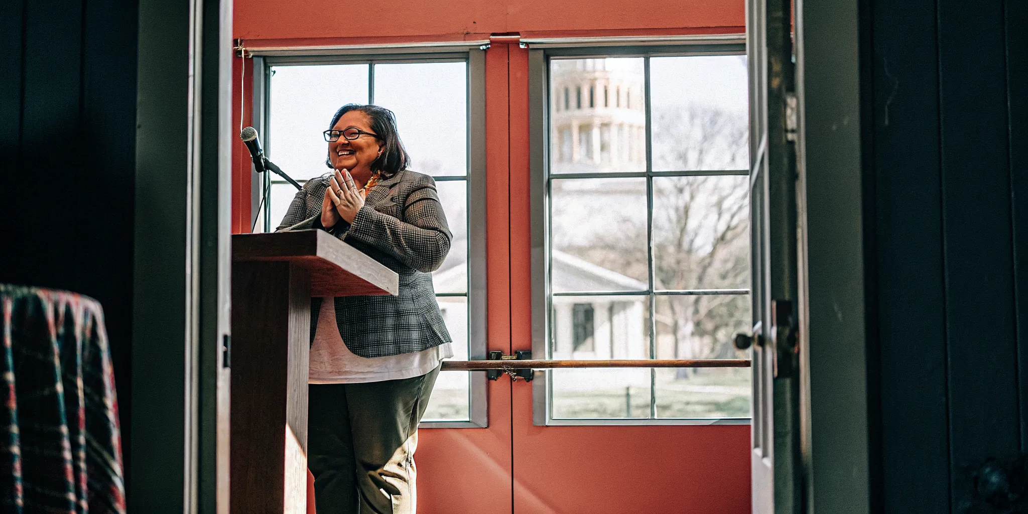 A confident celebrant at a lectern preparing to officiate, with the Ohio state capitol in the distance