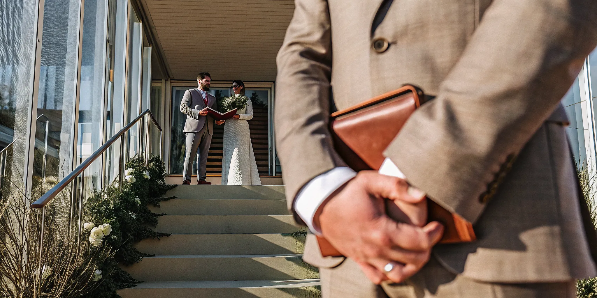 A wedding officiant leads a couple's marriage ceremony while reading from a book.