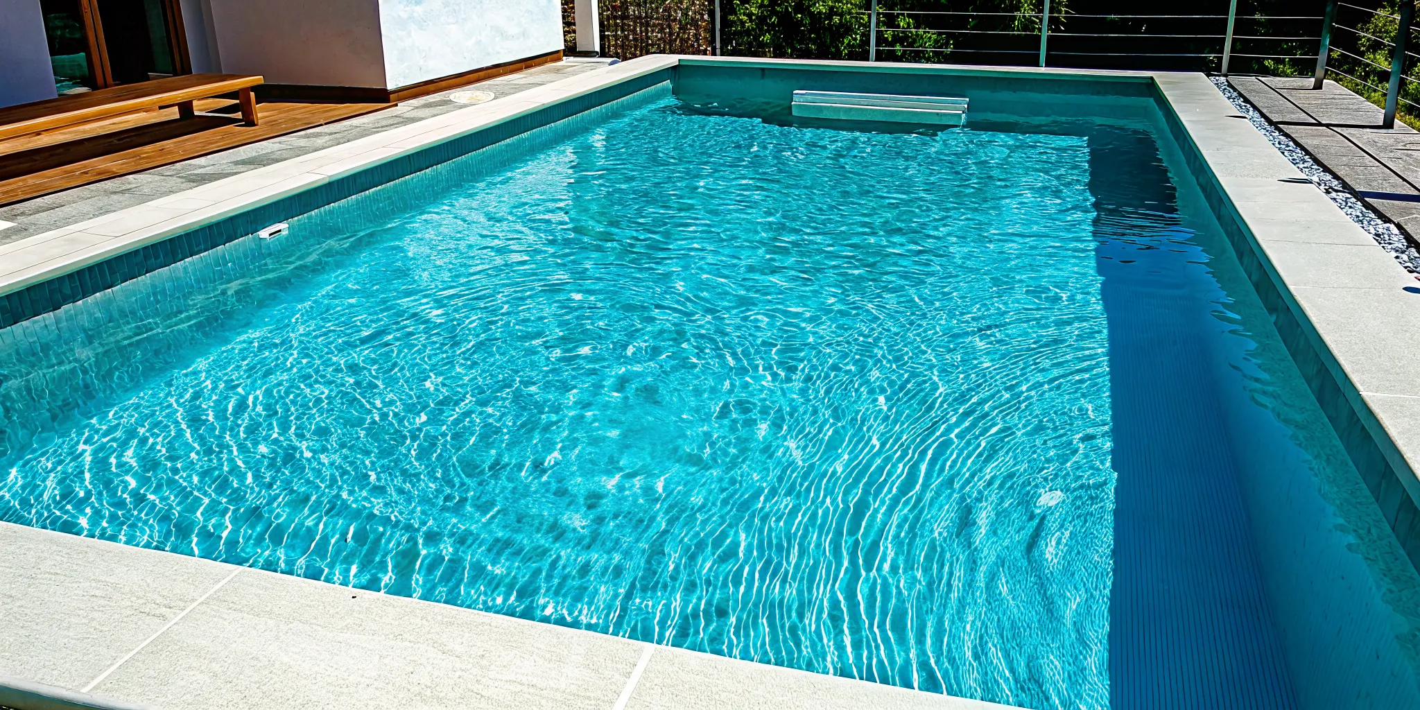 A modern plunge pool with sleek stone decking in a compact backyard setting.