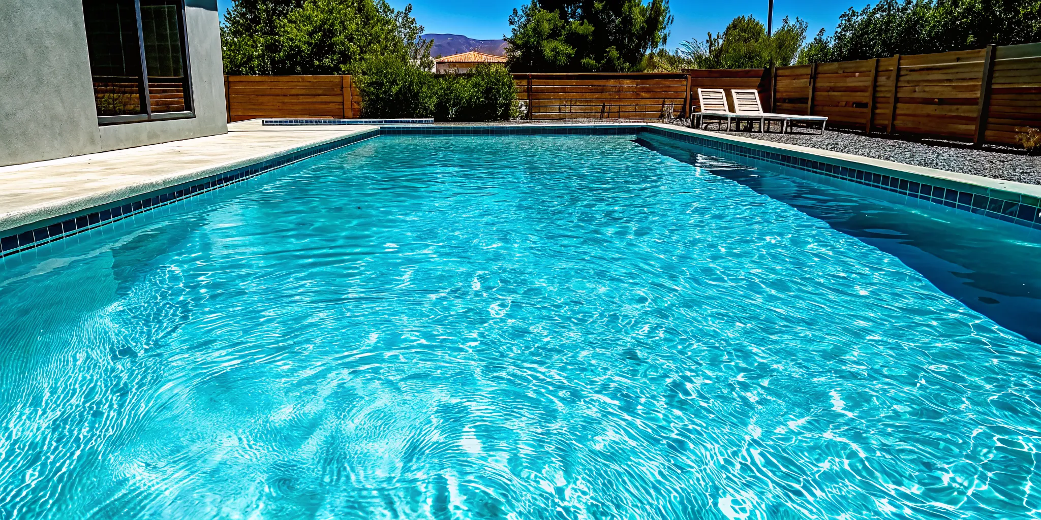 A modern backyard pool remodel with updated tile, a project by professional pool remodeling companies.