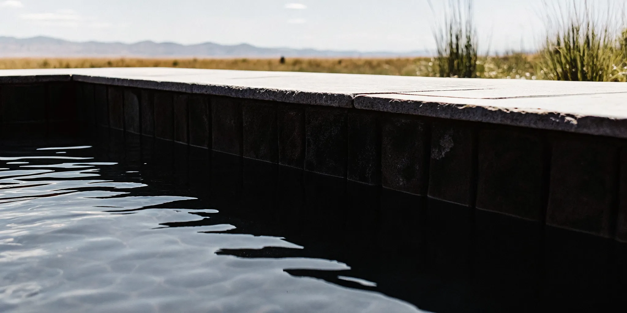 Textured pebble aggregate pool finish with rippling clear water in Colorado sunshine