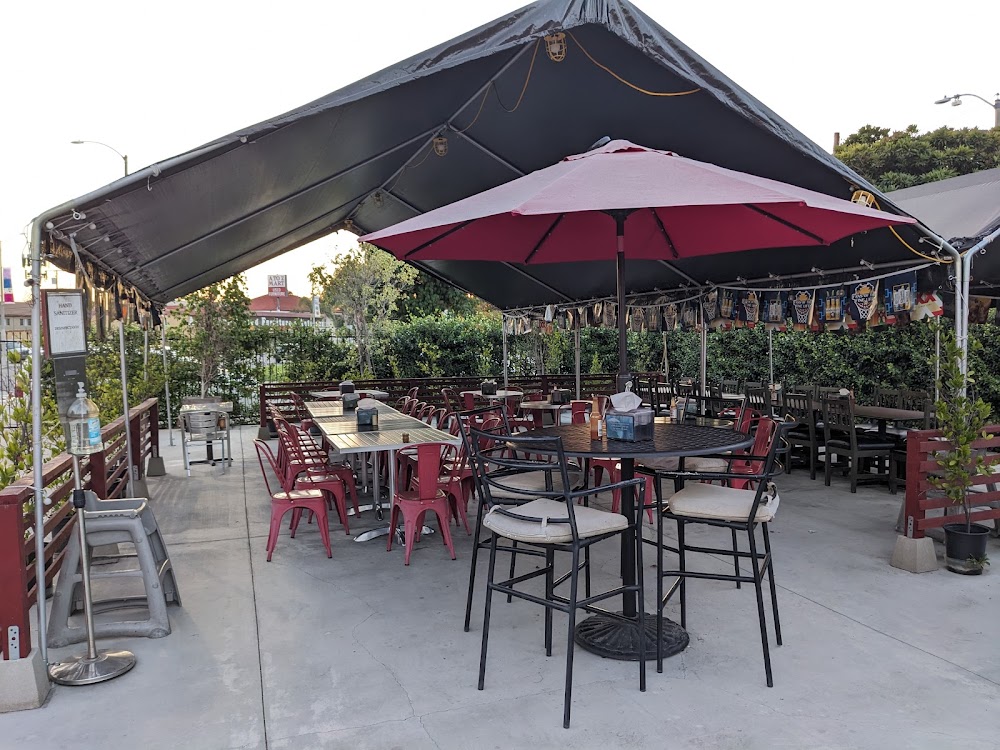 A black umbrella with a red top is over a table with chairs.