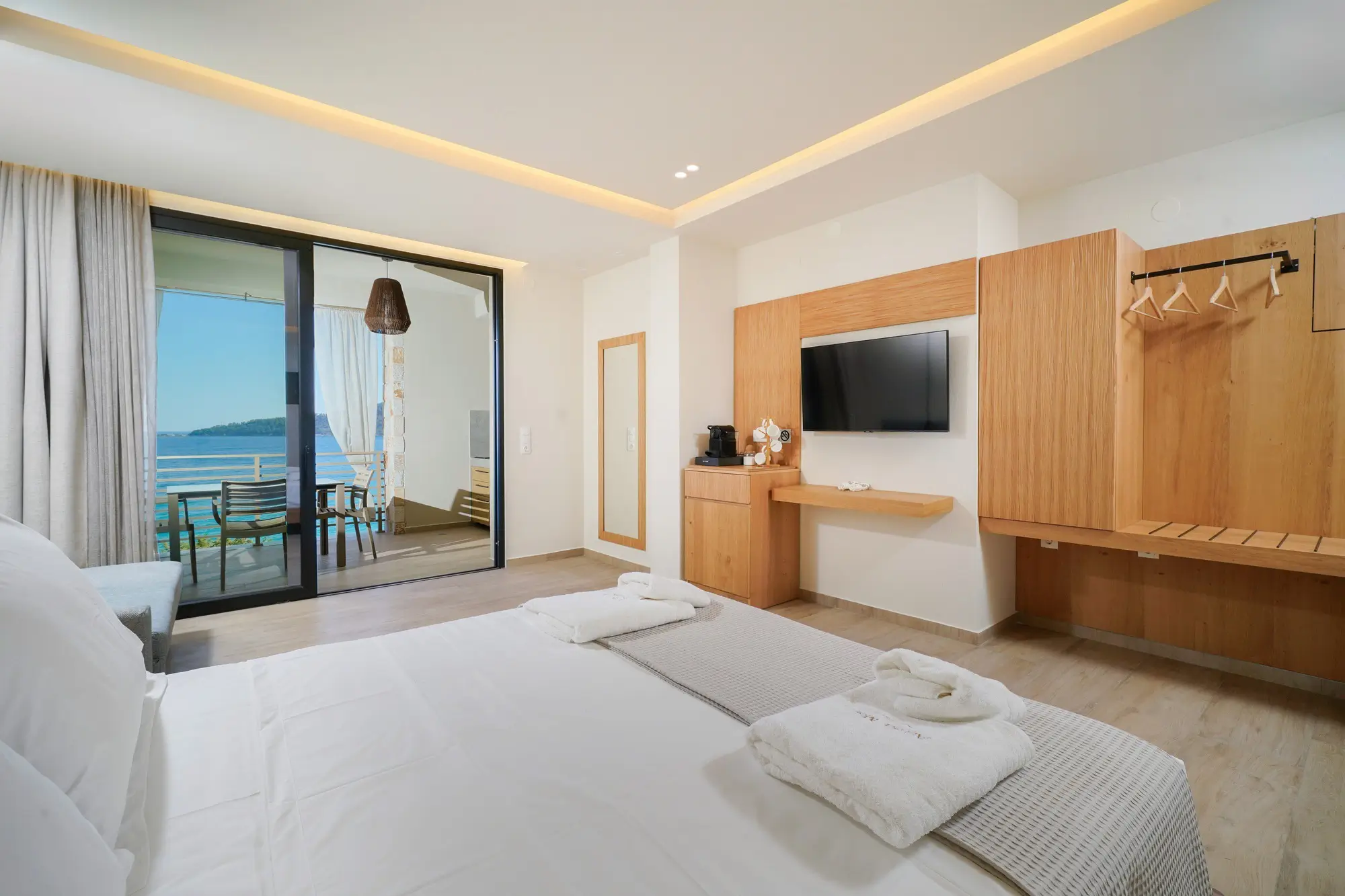 Suite bedroom with COCO-MAT king bed, oak TV unit and sea view through glass doors | Bedroom