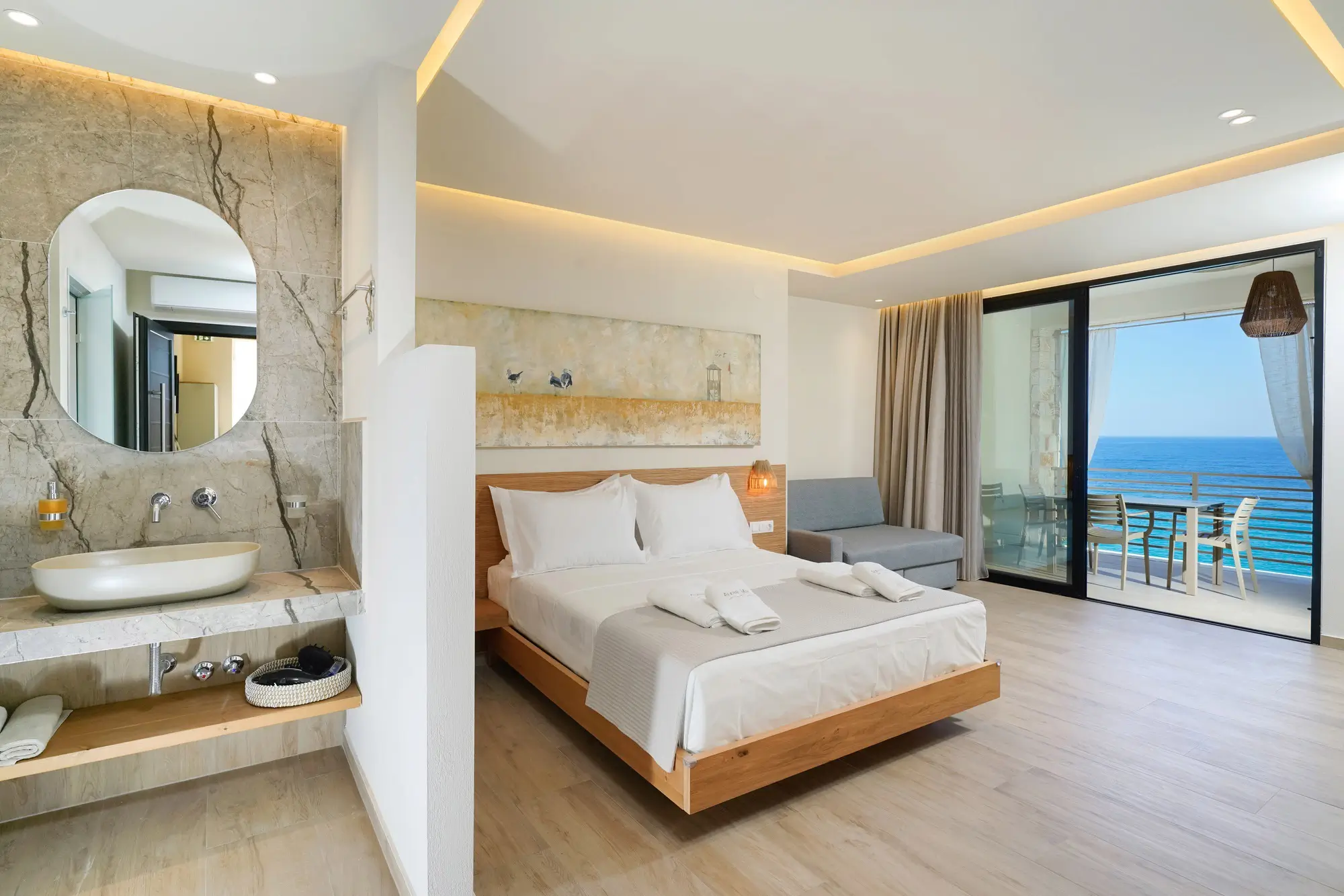 Suite bedroom with open marble bathroom and coastal wall art | Bedroom