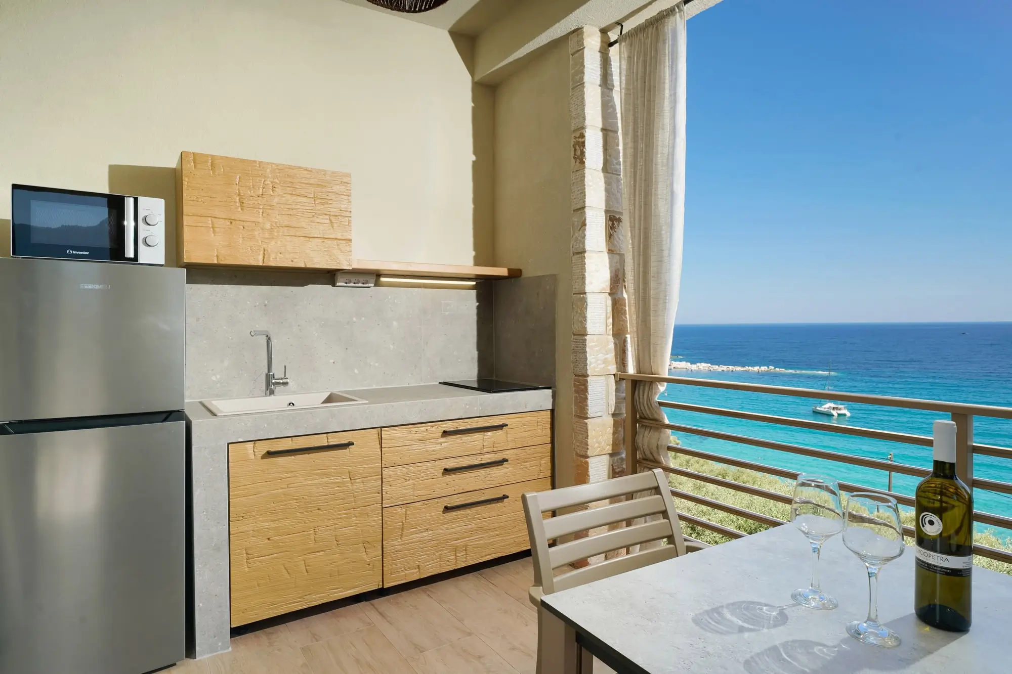 Outdoor kitchen with induction hob, fridge and sea backdrop | Kitchen
