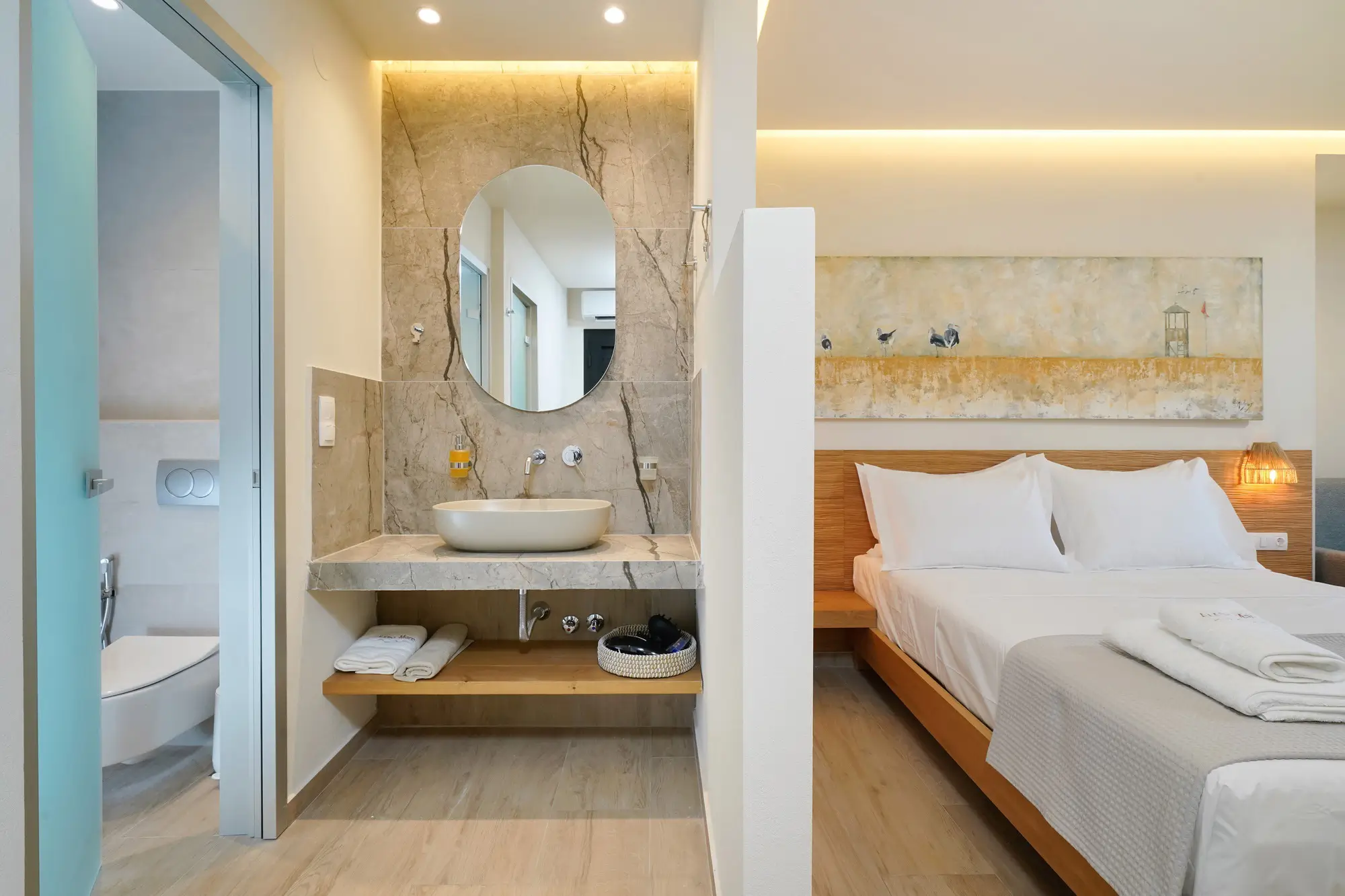Suite bedroom with open marble bathroom and coastal wall art | Bedroom
