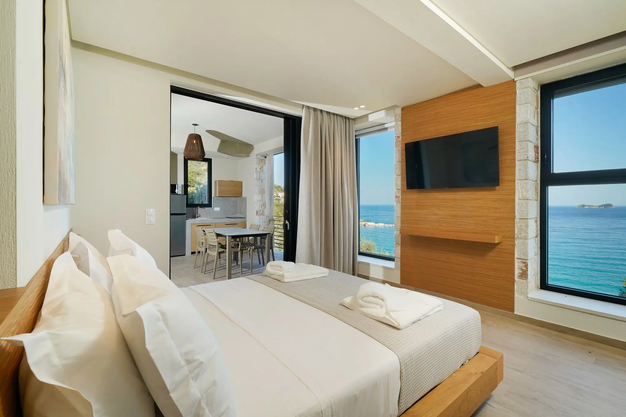 King bedroom opening to outdoor kitchen and Aegean sea terrace beyond | Suite