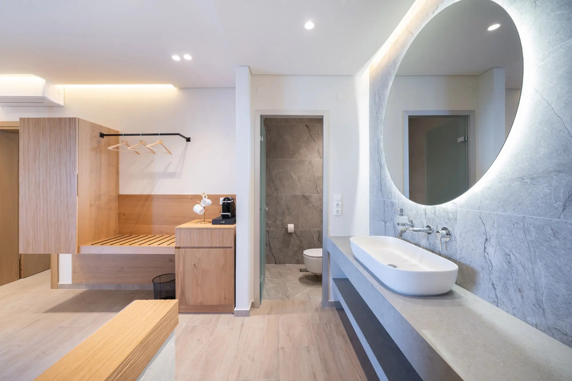 Open-plan bathroom with marble sink, backlit mirror and wood joinery beyond | Bathroom