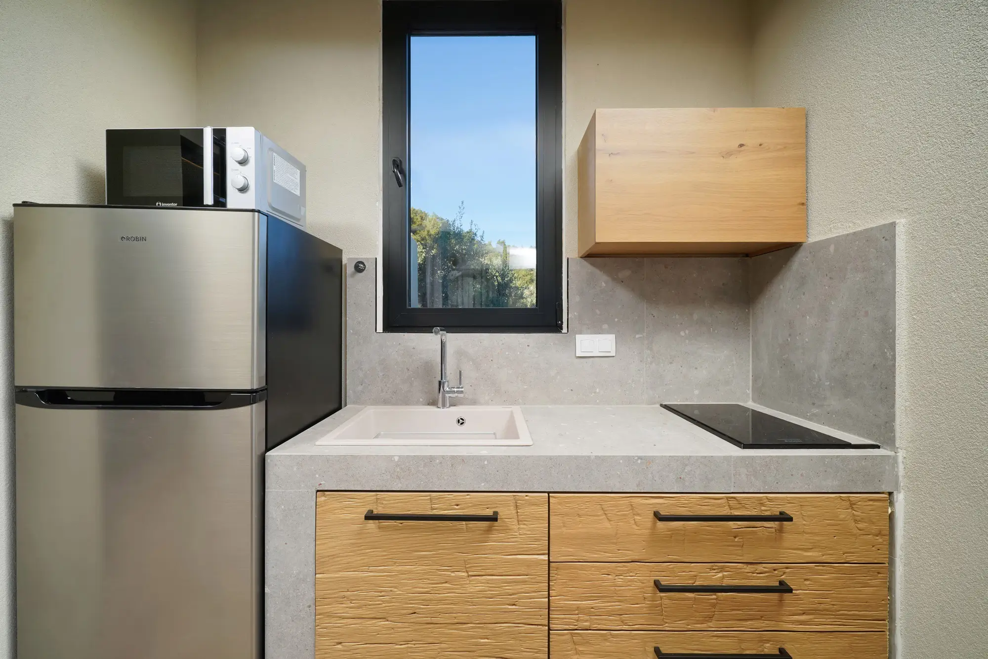 Outdoor kitchen detail with fridge-freezer, microwave, hob and stone countertop | Outdoor Kitchen