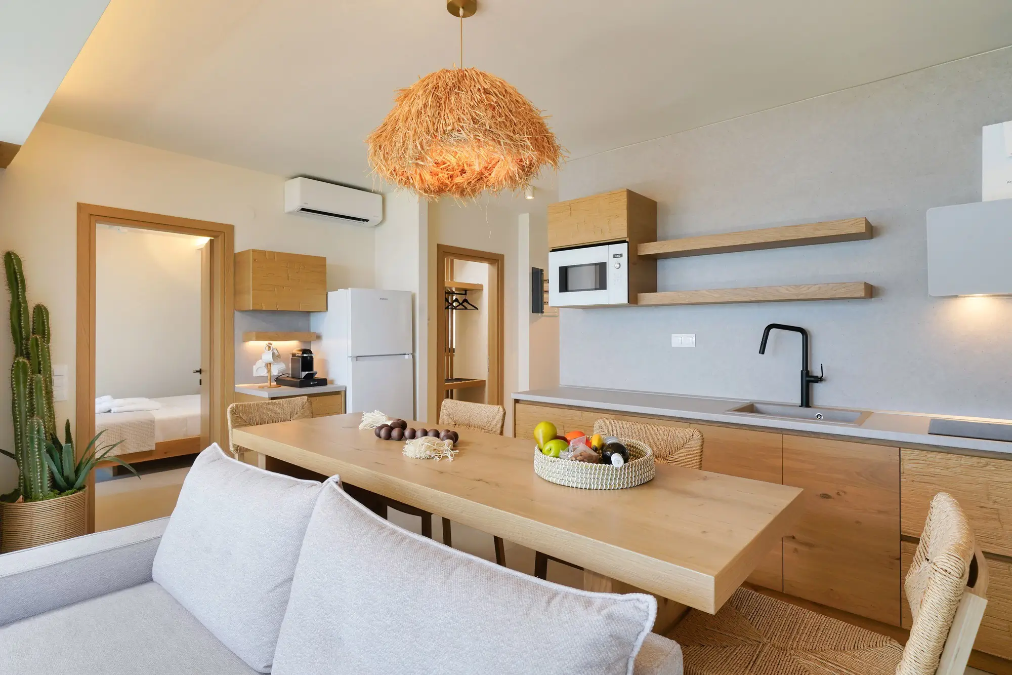 Open-plan dining and living area with sea-facing glass doors and raffia pendant | Living Area