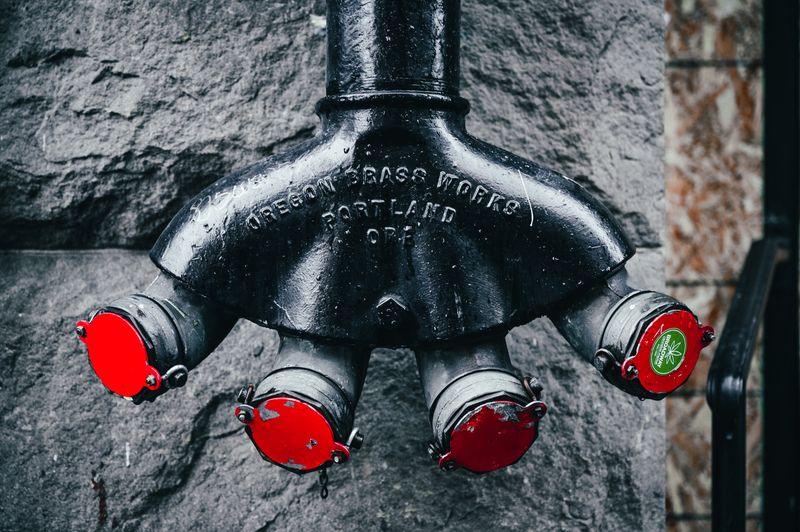 Modern metal water distribution system for supplying water to hoses for fire extinguishing placed near rough gray wall on street
