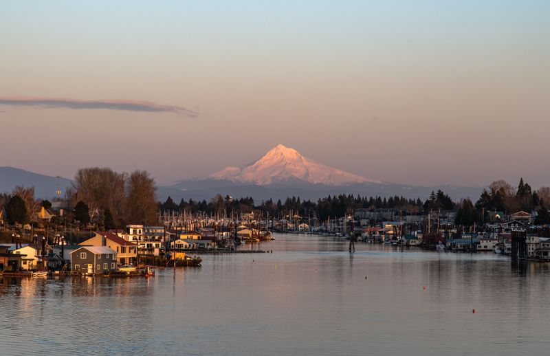 A captivating view of Mount Hood at sunset with a serene marina and houses along the river in Oregon, USA.