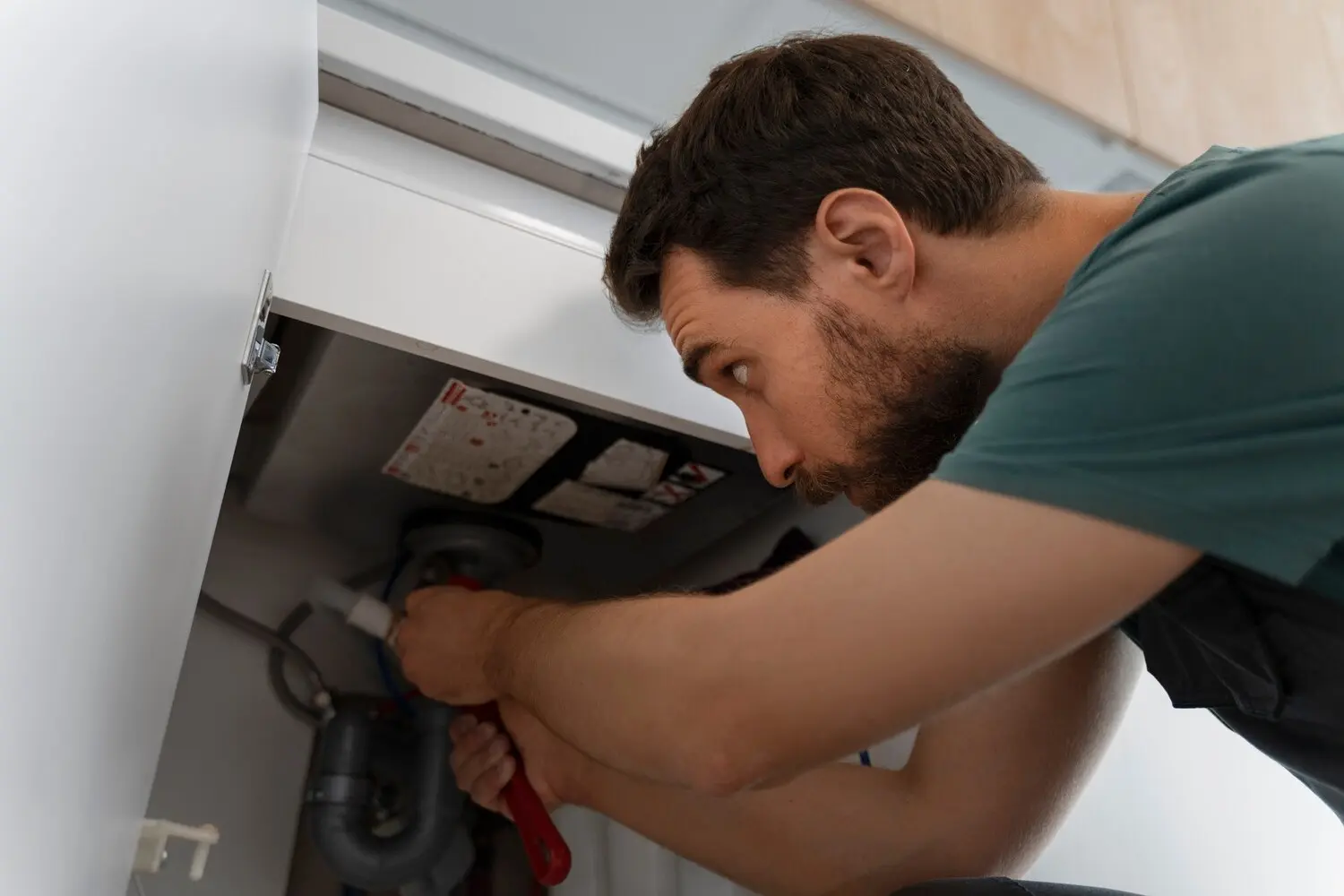 Plumber connecting pipes beneath a sink during an ADU plumbing installation