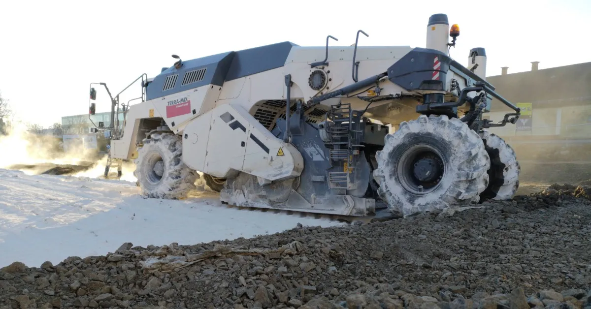 Large Terra-Mix construction machine working on uneven terrain with dust and soil around.