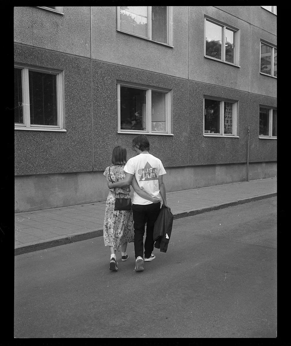 Smiling young woman with shoulder-length hair wearing a white shirt and dark jacket against a plain background.