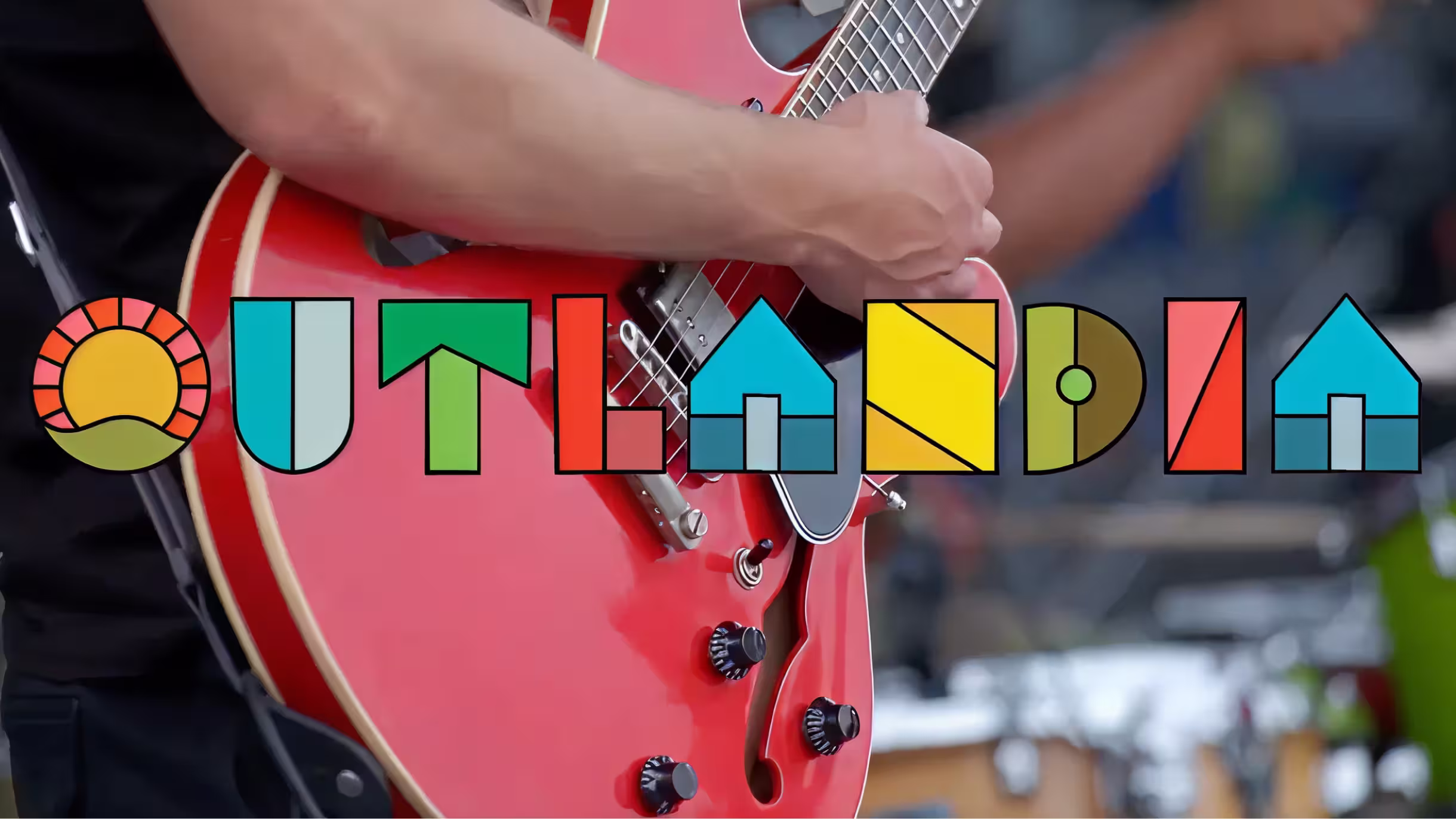 Colorful Outlandia wordmark over a guitarist performing
