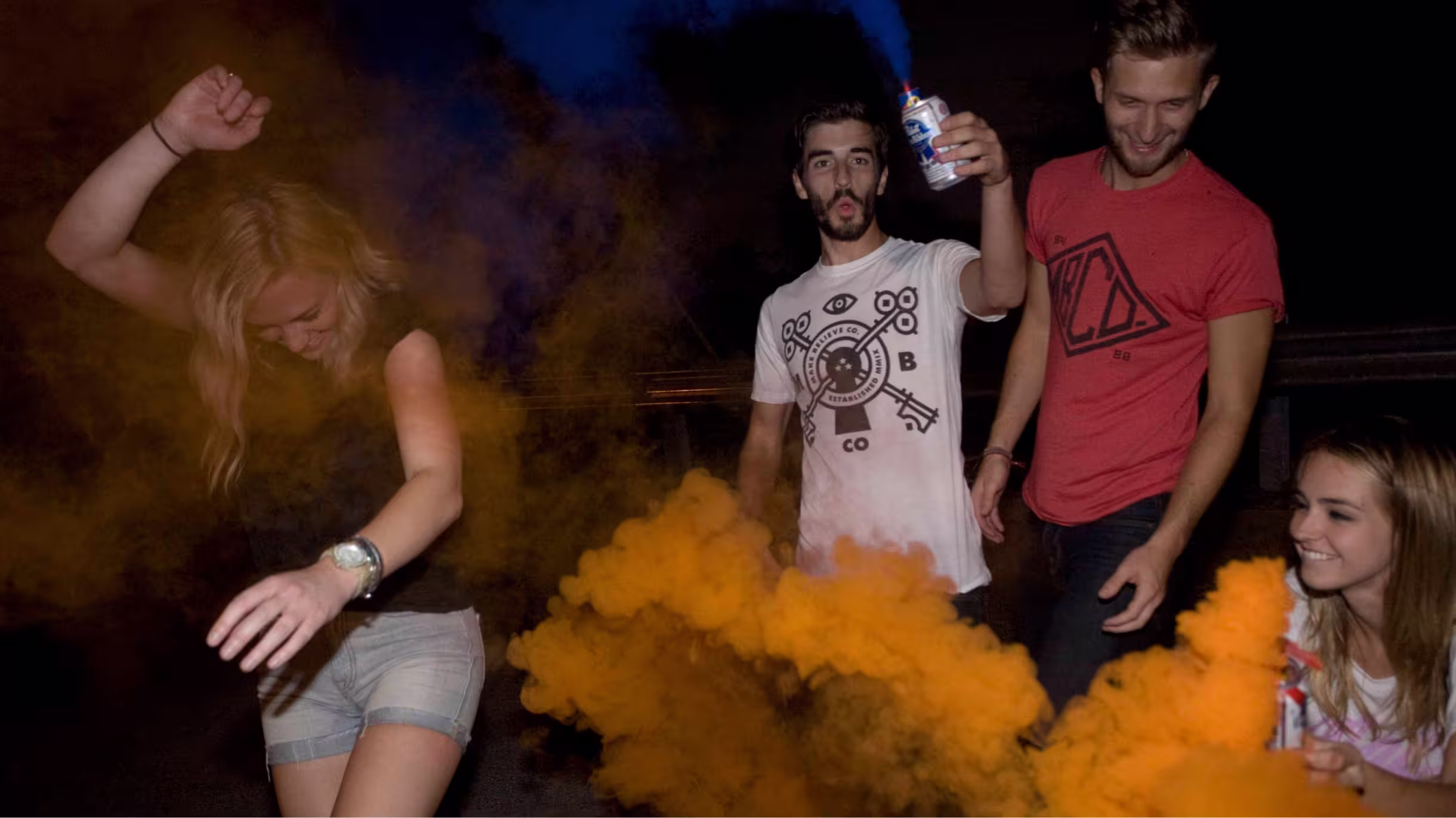 Group wearing Make Believe apparel amid orange smoke