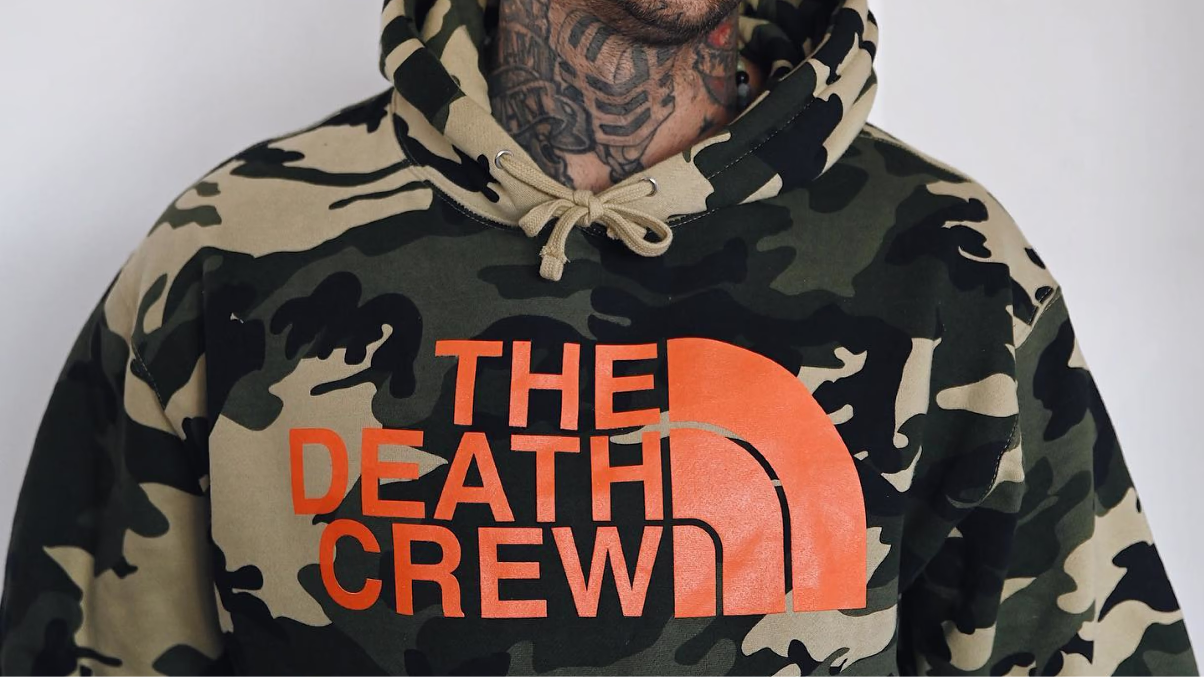 Tattooed person wearing a camouflage Death Crew hoodie