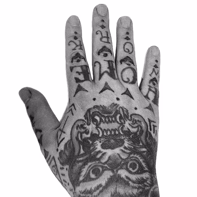 Black-and-white tattooed hand featuring a tiger and symbols