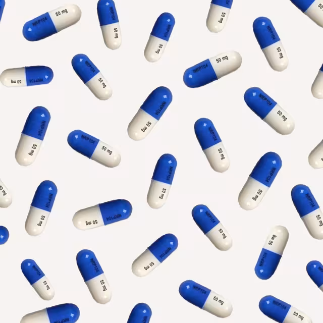 Scattered blue-and-white prescription capsules on a cream background
