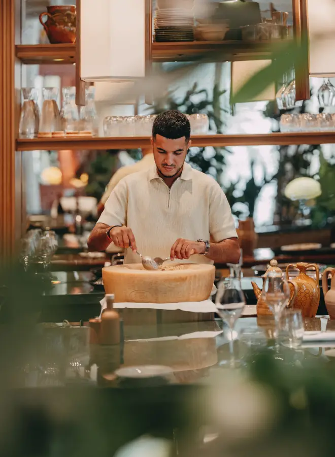 Un homme prépare un plat dans une grande moitié de fromage dans une cuisine chaleureuse.